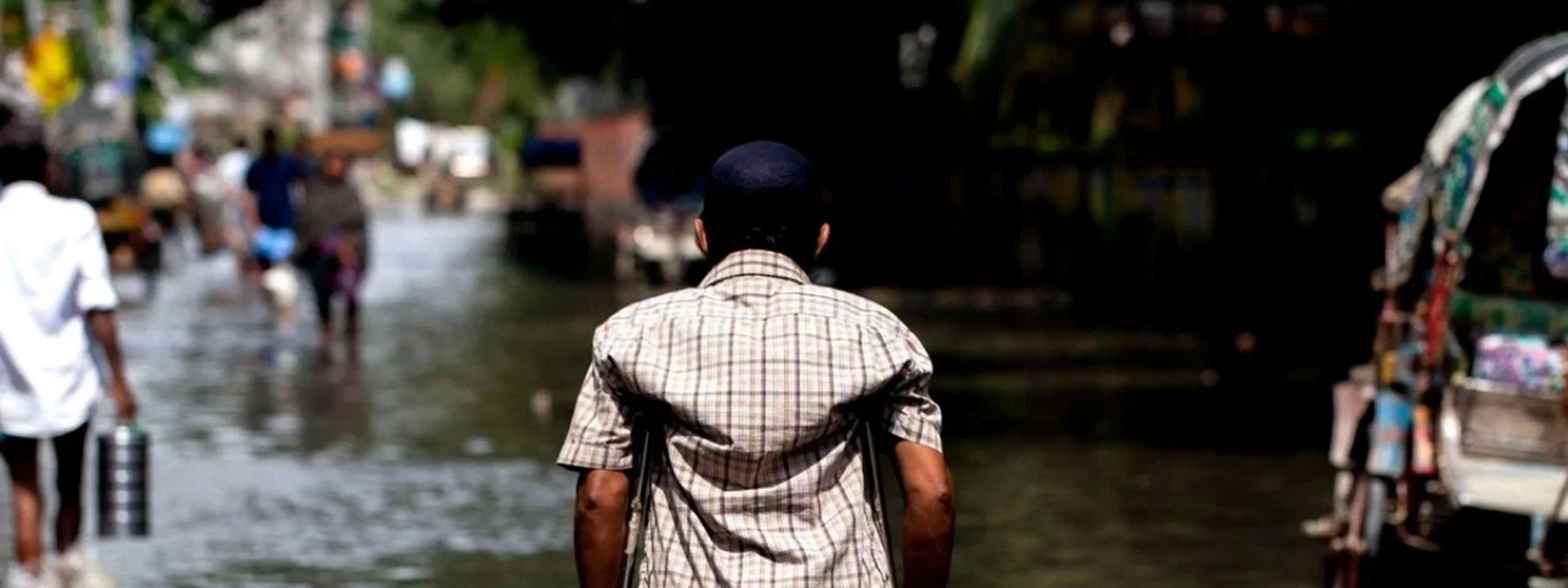 Person using crutches walks through a flooded street, navigating high water after heavy rains